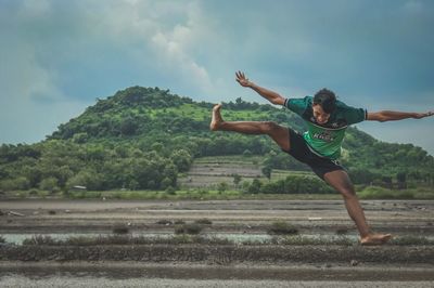 Young man jumping with arms outstretched against mountain