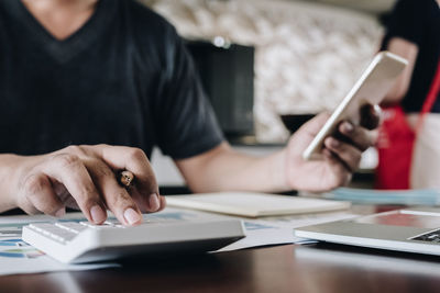 Midsection of man using smart phone on table