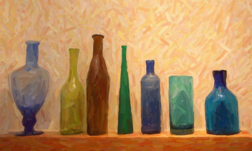 Various bottles on glass table against wall