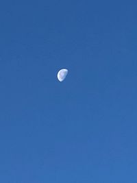 Low angle view of moon against clear blue sky