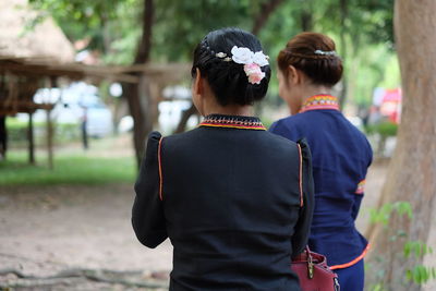 Rear view of friends standing against trees