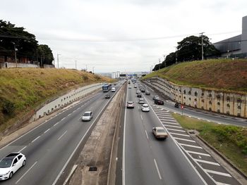 Vehicles on road in city against sky