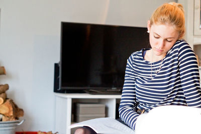 Young woman sitting on sofa at home