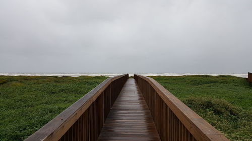 Footbridge over land against sky