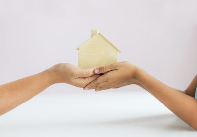 Close-up of hand holding book against white background