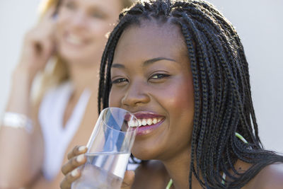 Close-up portrait of a smiling young woman drinking drink