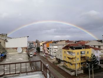 Rainbow over buildings in city against sky