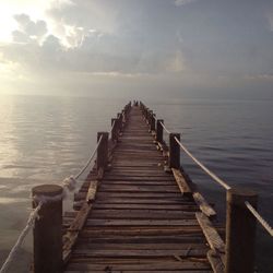 Pier over sea against sky during sunset