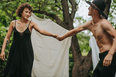 Young couple standing against trees