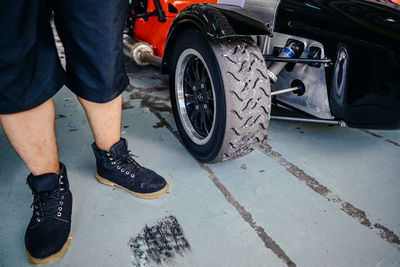 Low section of man standing by sports car in garage