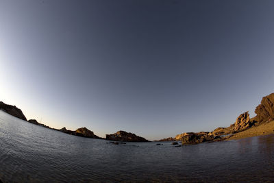 Scenic view of sea and mountains against clear sky