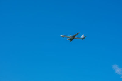 Low angle view of airplane against clear blue sky