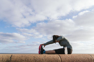 Woman sitting down stretching her legs.