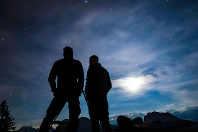 Silhouette men standing against sky at night