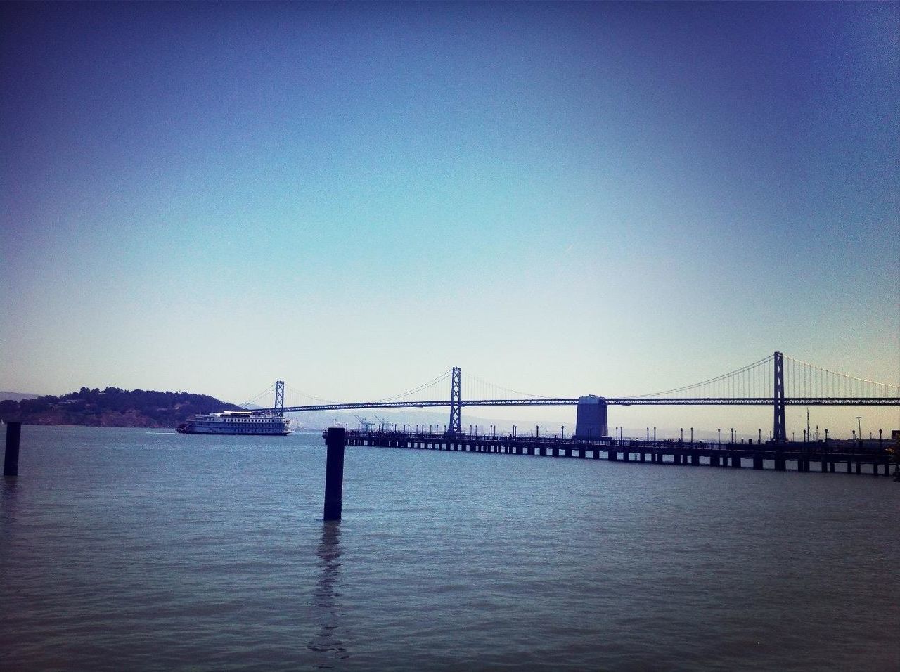 connection, bridge - man made structure, architecture, built structure, water, suspension bridge, engineering, bridge, clear sky, copy space, waterfront, river, transportation, sea, travel destinations, golden gate bridge, blue, international landmark, sky, long