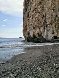 Rock formation on beach against sky