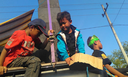 Low angle view of boys sitting on vehicle