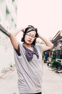 Young woman with arms raised standing in the ally