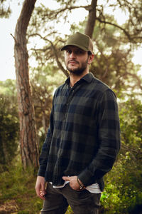 Portrait of young man standing against trees