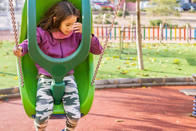 Girl playing on swing at playground