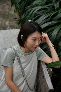 Portrait of young woman standing against plants