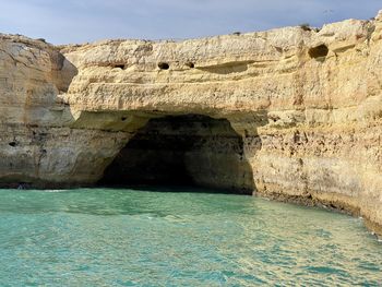 Rock formation by sea against sky