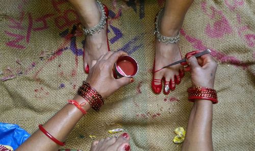 High angle view of woman applying henna on foot