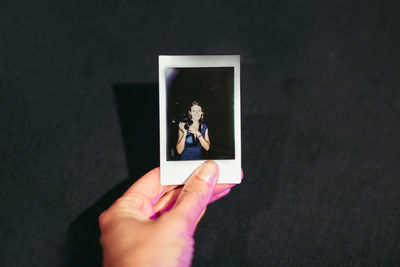 Cropped image of photographer holding picture frame over table