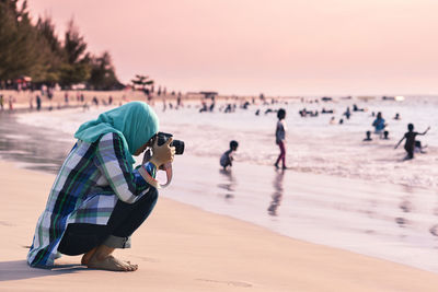 Side view of woman photographing at beach