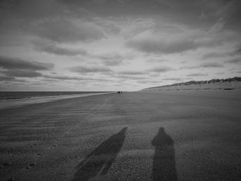 Shadow of people on road against sky