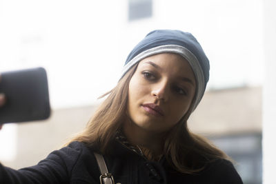 Young woman with cap outside taking a selfie