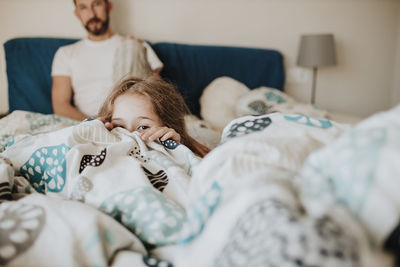 High angle view of siblings lying on bed