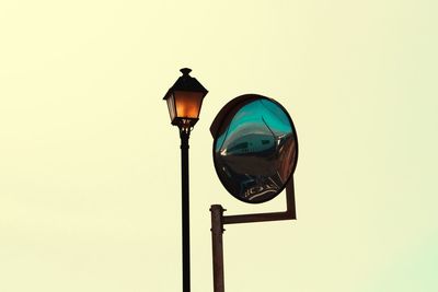 Low angle view of street light and road mirror against clear sky