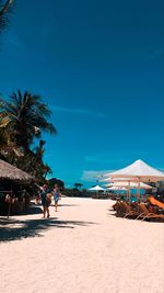 People at beach against blue sky