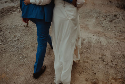 Low section of couple walking on dirt road