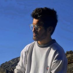 Portrait of young man standing against blue sky