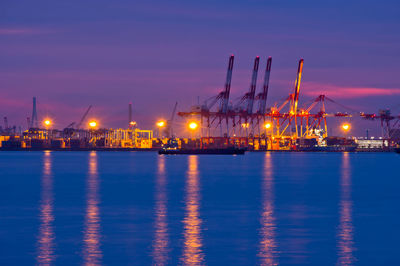 Illuminated commercial dock by sea against sky