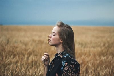 Side view of woman standing on field against sky