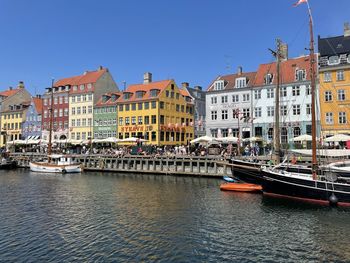Sailboats moored on canal by buildings against sky in city