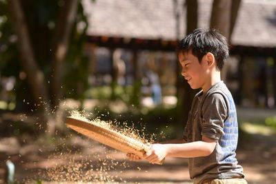 Side view of boy winnowing crops