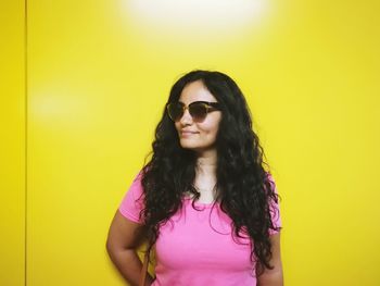 Smiling young woman against yellow wall