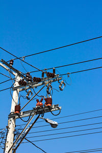 Low angle view of electricity pylon against clear blue sky