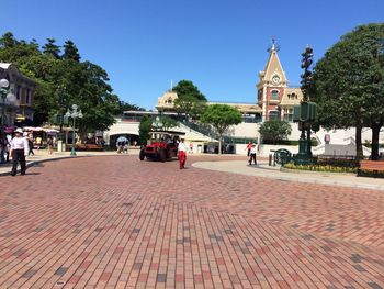 People walking on street amidst buildings against sky in city