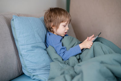 Side view of boy lying on bed at home