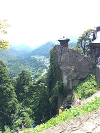 People on building by mountains against clear sky