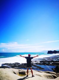 Rear view of man standing on beach against sky