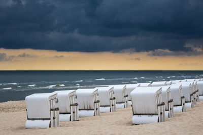 Hooded chairs on beach against sky