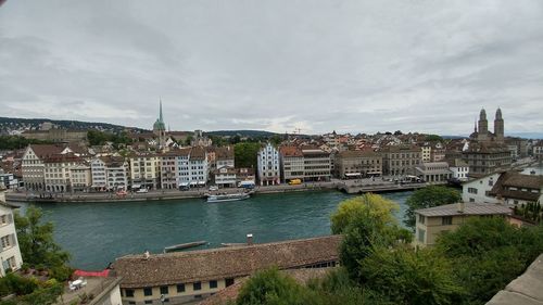 High angle view of river by buildings in town against sky