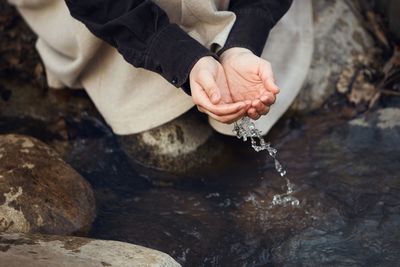 High angle view of hand holding rock in water