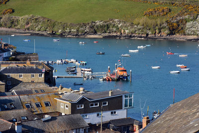 High angle view of sailboats moored on sea by buildings in city